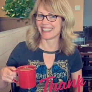 A woman holding a red mug in her hand.