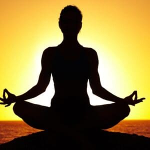 A person sitting in the lotus position with their hands in yoga pose.
