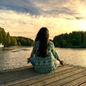 A woman sitting on the dock of a lake