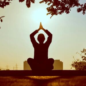 A person is sitting in the sun doing yoga.