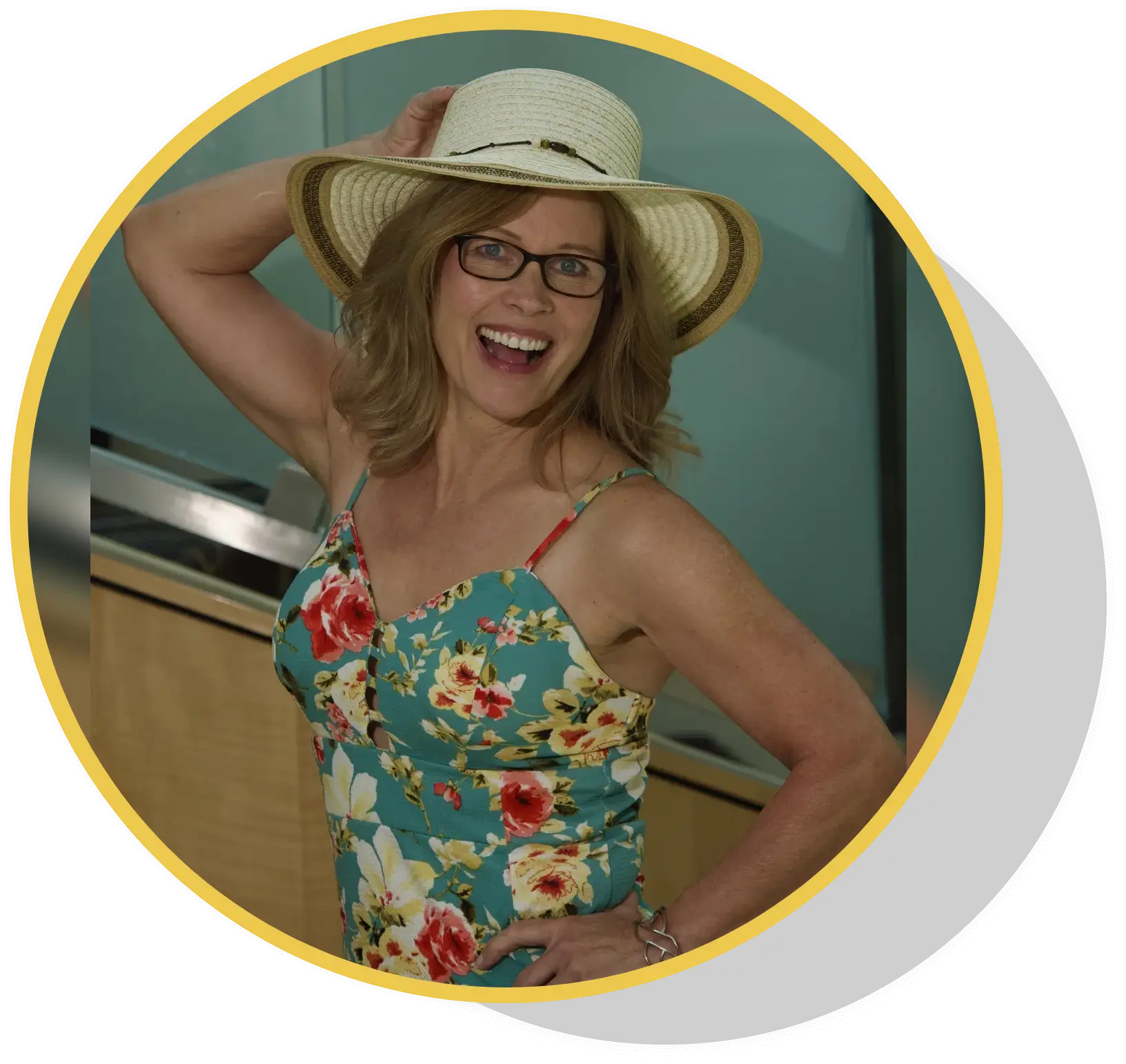 A woman in floral shirt and hat smiling for the camera.