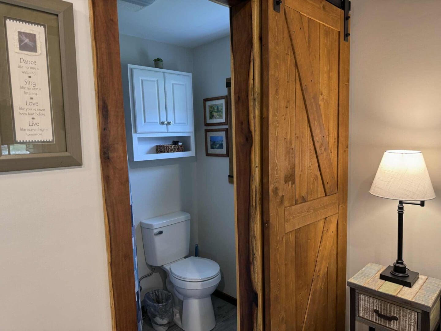 Bathroom with wooden sliding door and lamp.