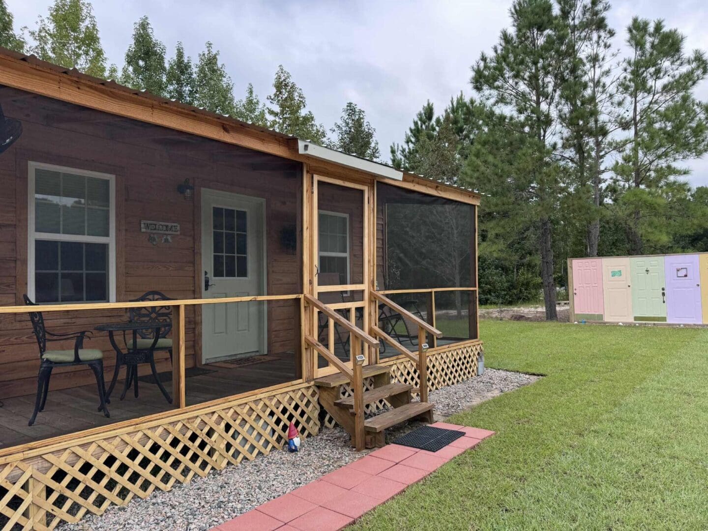 Wooden cabin with screened porch and lawn.