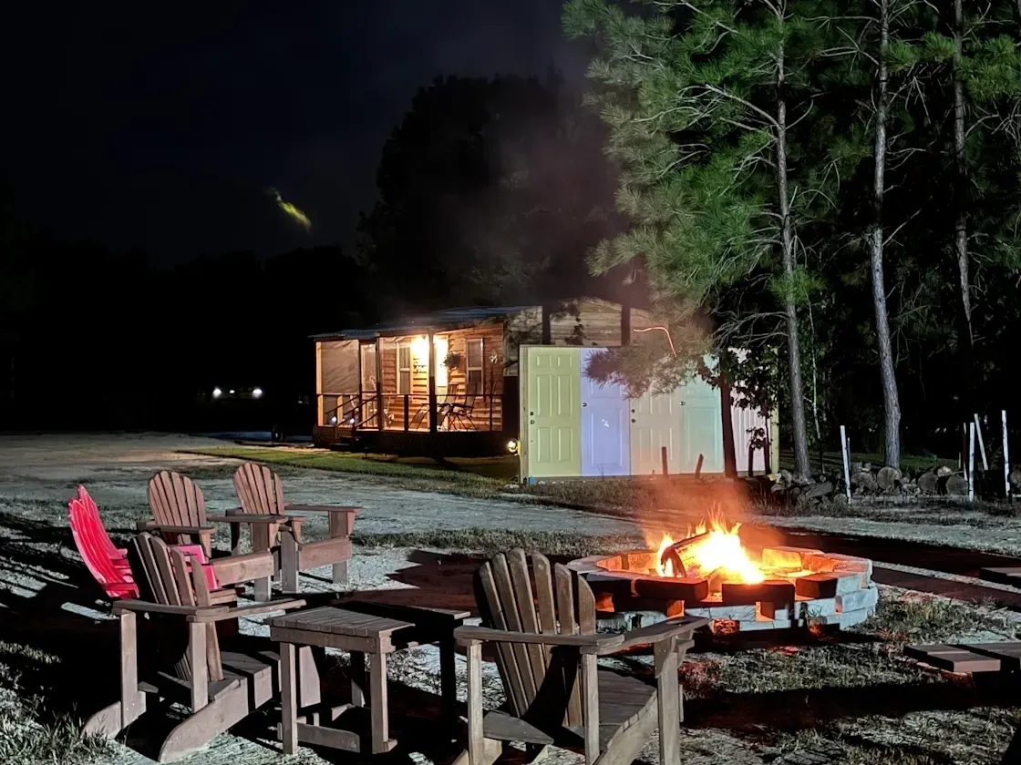 Nighttime campfire with chairs and cabin.
