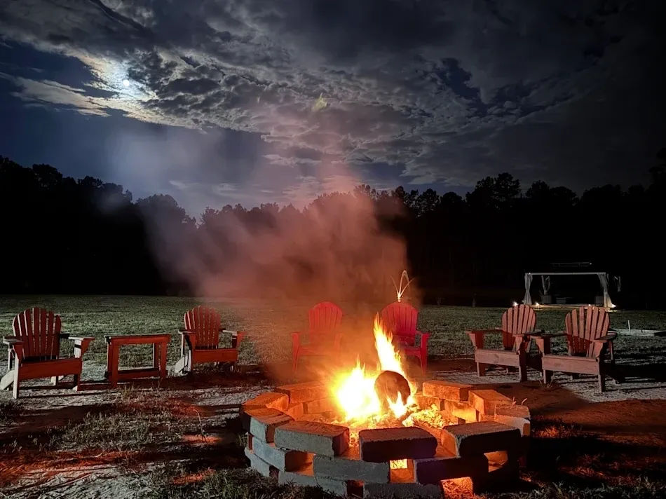 Campfire under a cloudy, moonlit sky.
