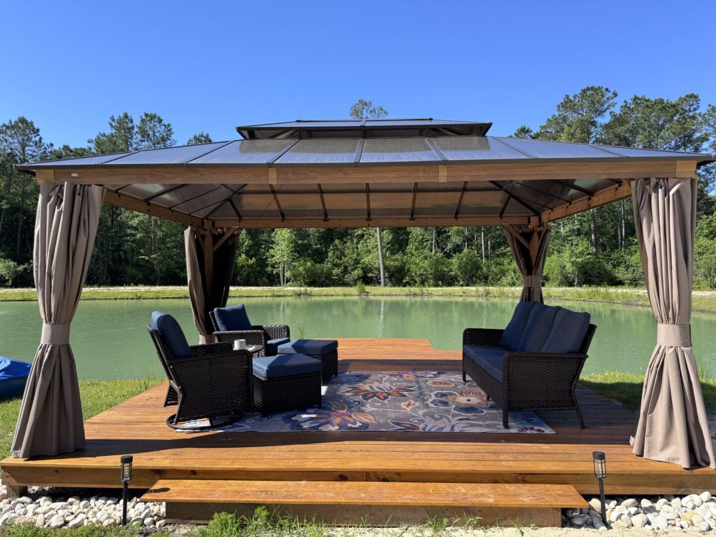 Gazebo by a pond with outdoor furniture.