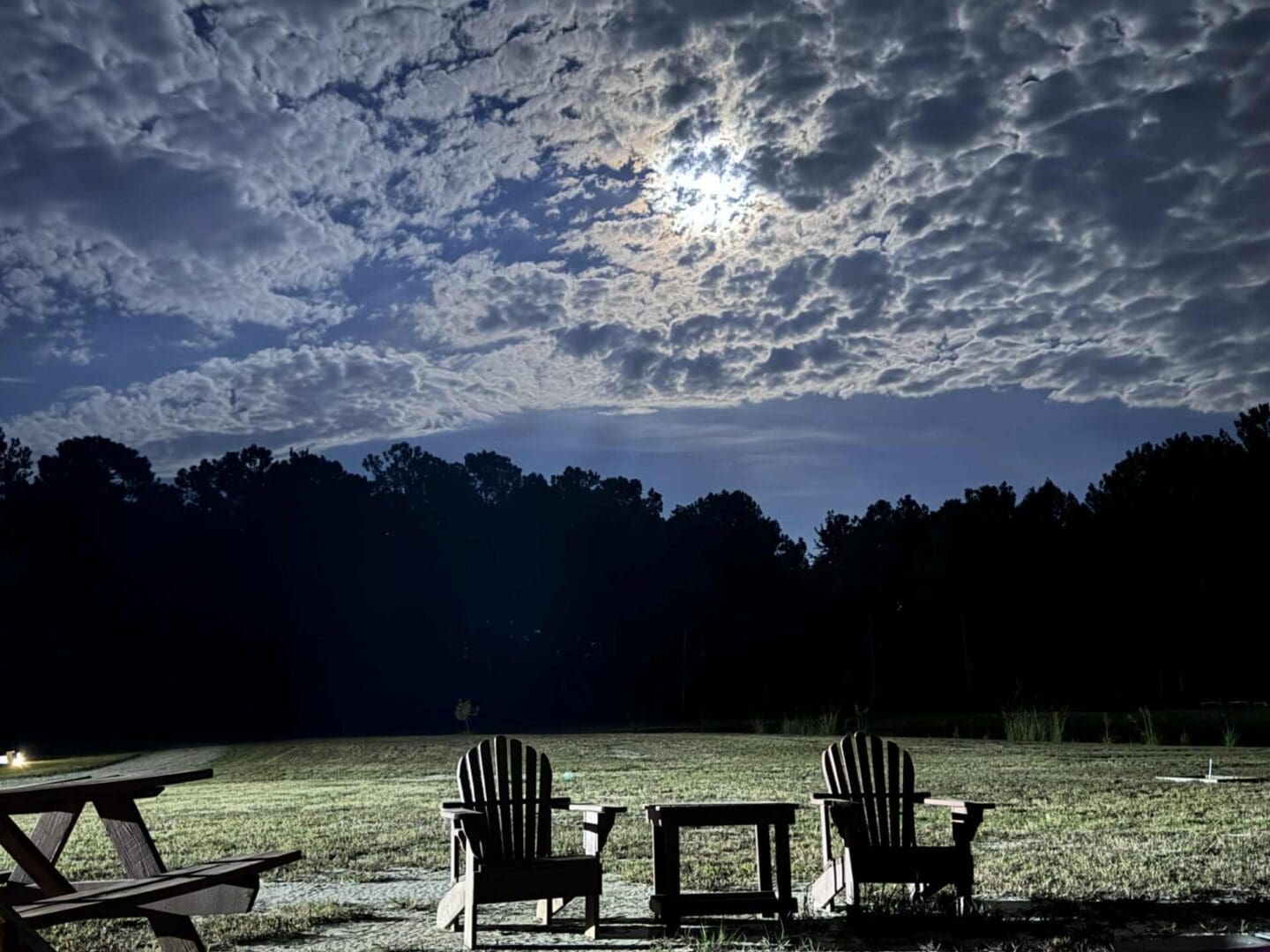 Night sky over chairs and picnic table.