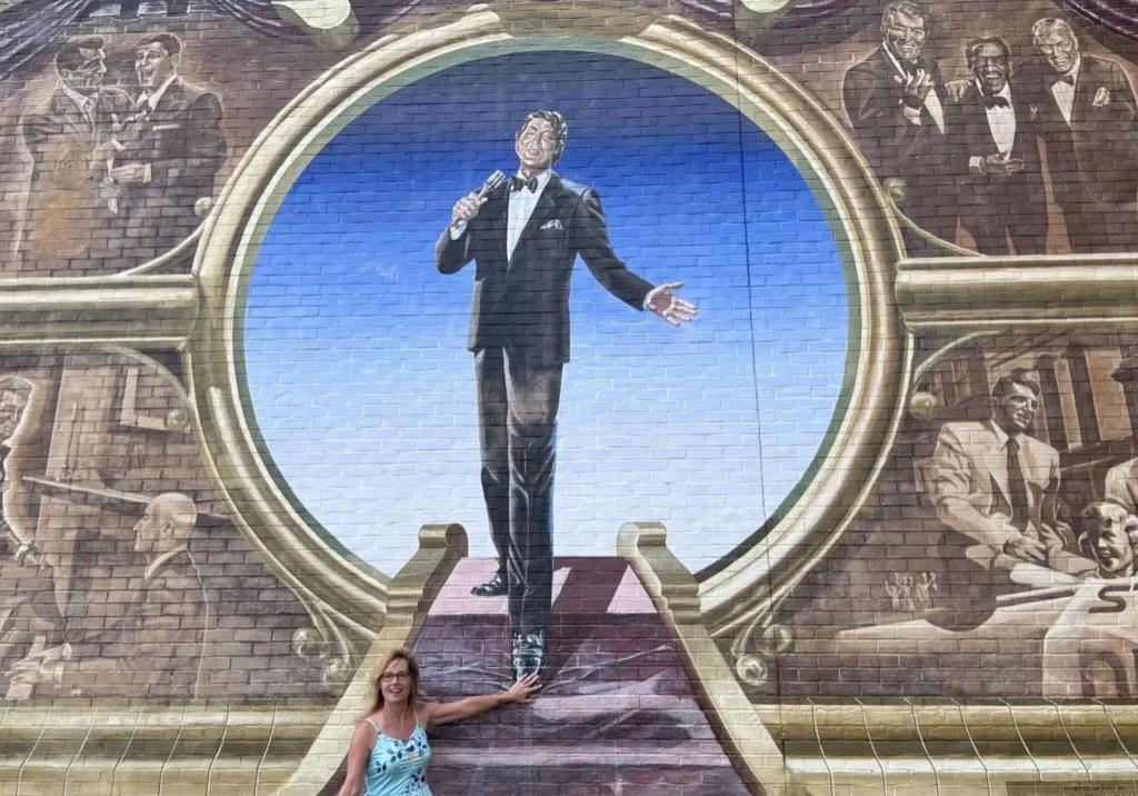 A woman in blue dress standing on stairs next to a mural.